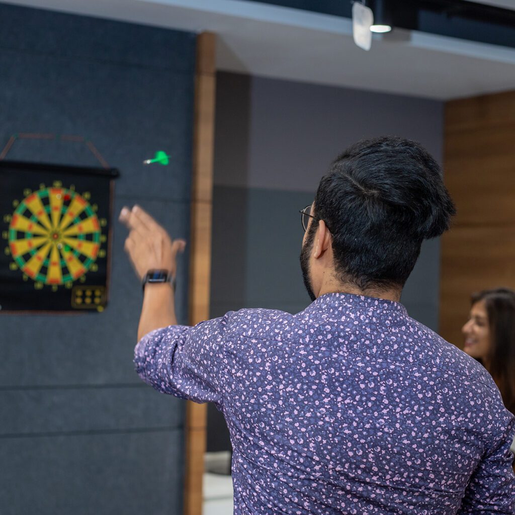 Trinity employee throwing a dart at a dartboard.