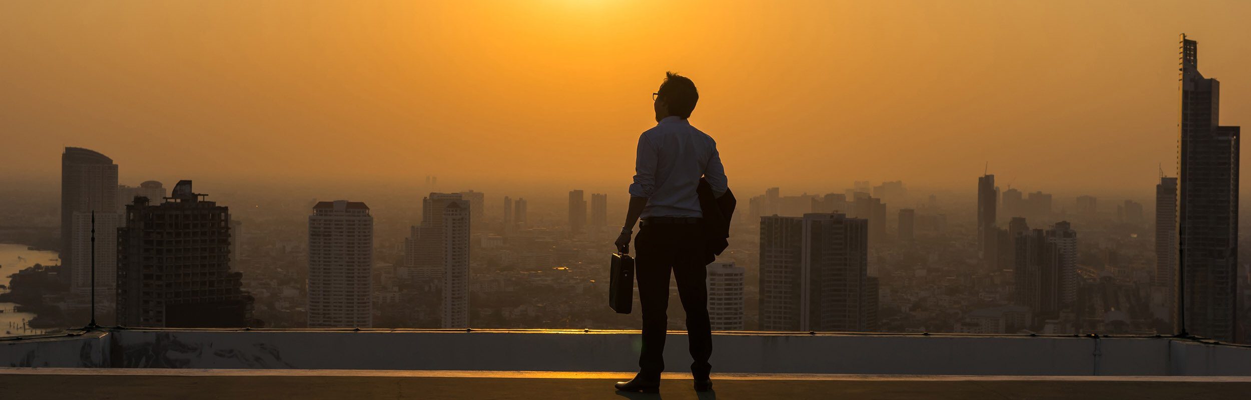 Business man looking into the sunset over a city
