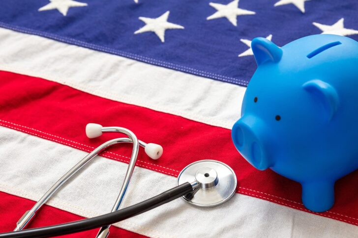 Medical stethoscope and piggy bank on a US of America flag, banner.