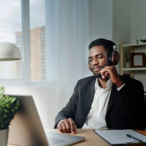 Man wearing noise canceling headphones while looking at a laptop