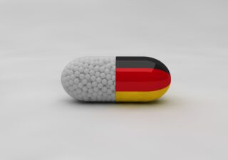 Pill with Germany flag on background and medical particles