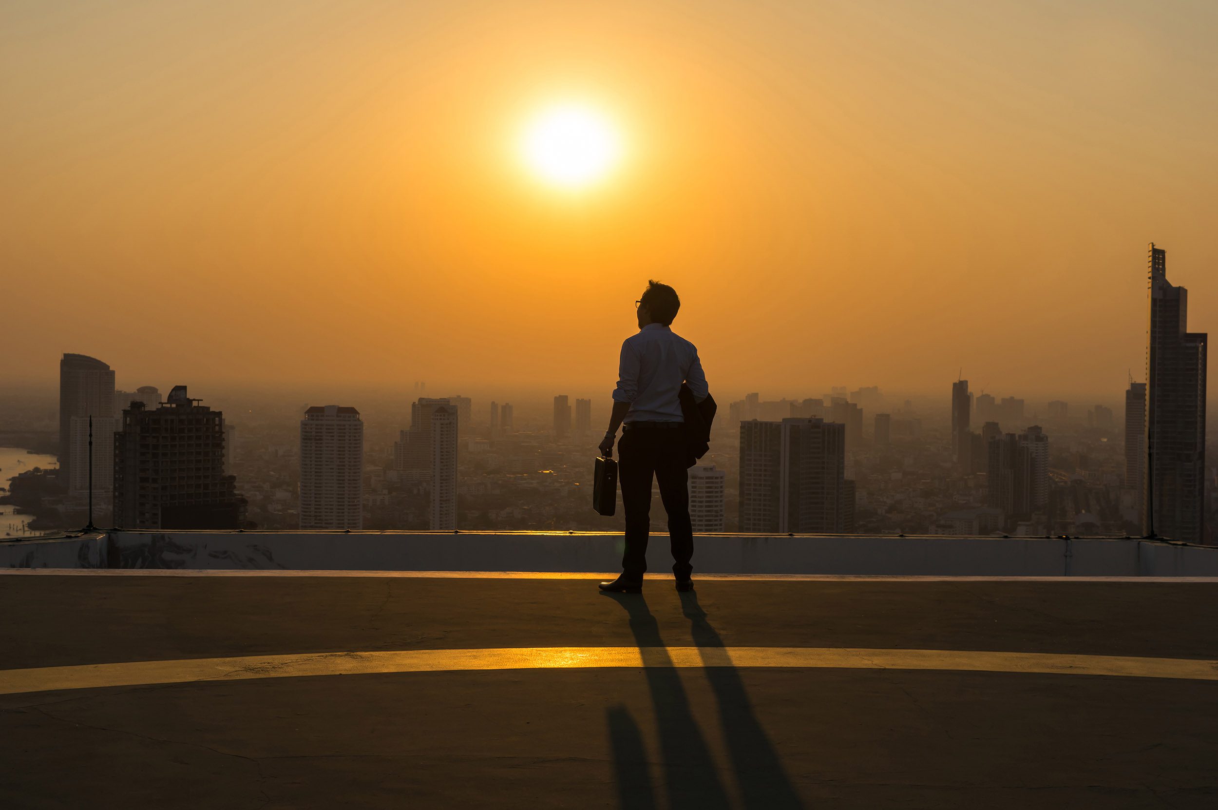 Business man looking into the sunset over a city